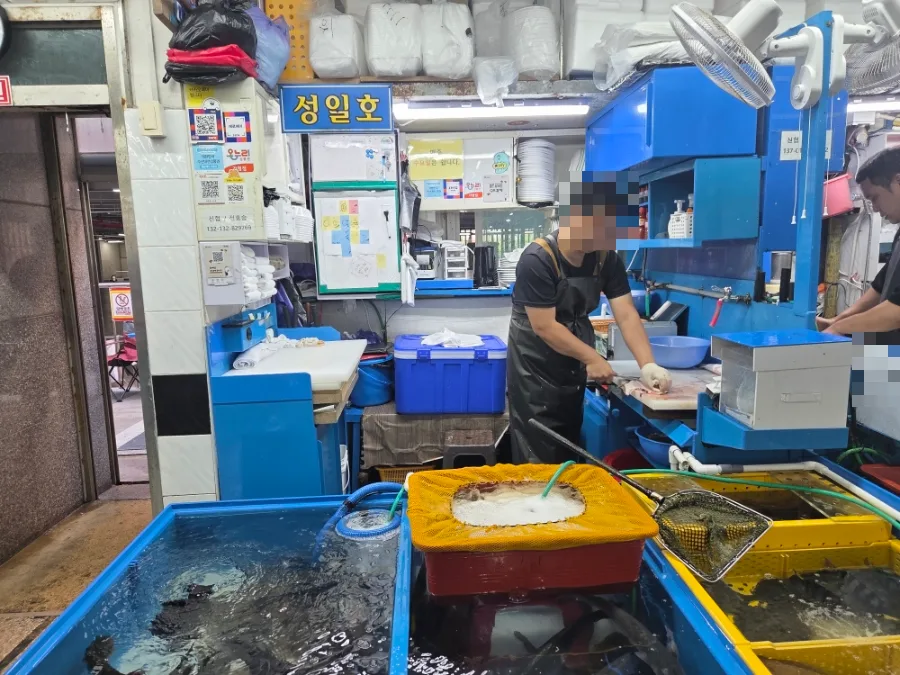 水槽の奥で魚をさばく店員