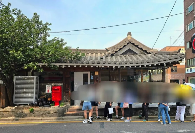 瓦屋根の店先に並ぶ人々
