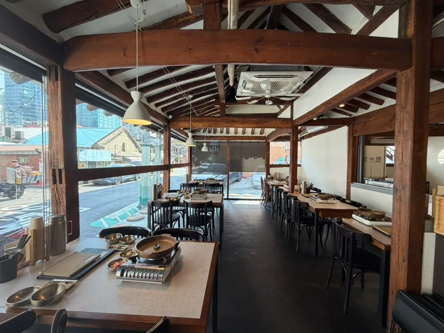 美米屋 新龍山店 — 木の梁と窓際のテーブル席