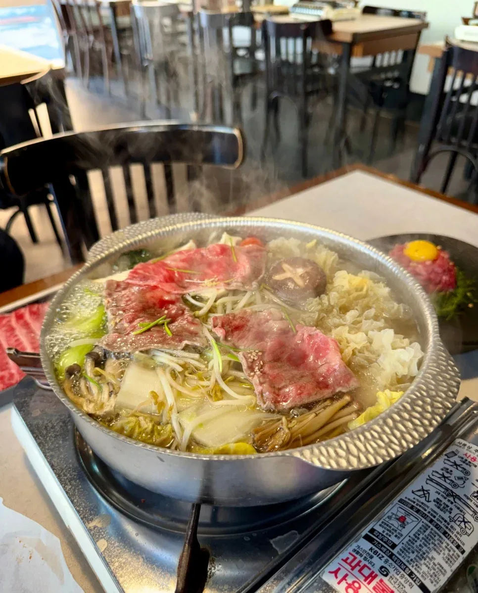 湯気の立つ鍋で煮える牛肉と野菜