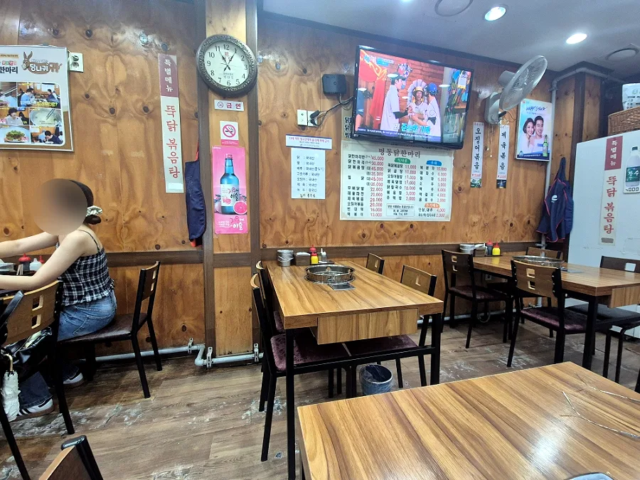 明洞タッカンマリ — 木の壁と鍋用コンロのあるテーブル