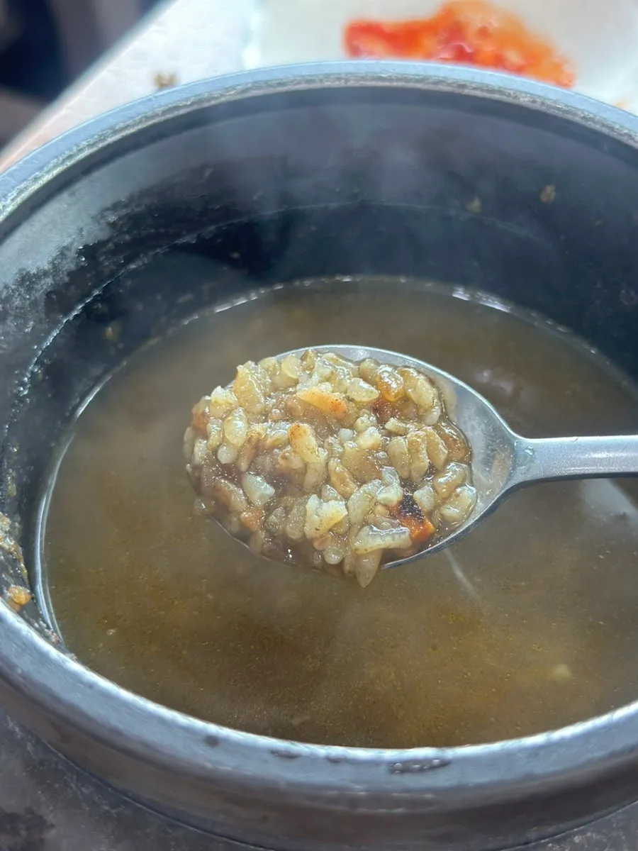 湯を注いだ石釜からすくうおこげ