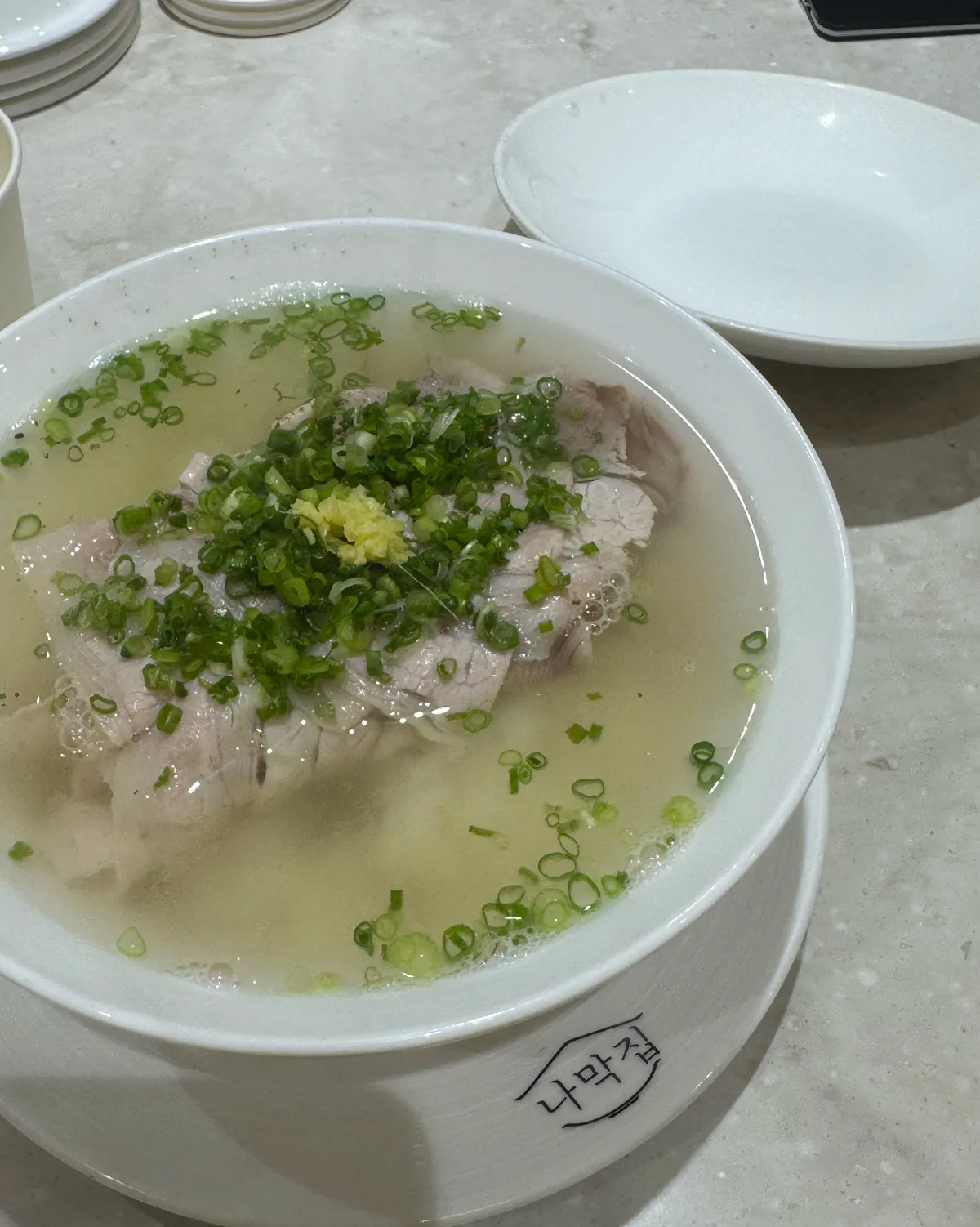澄んだスープに浮かぶ豚肉と青ねぎ