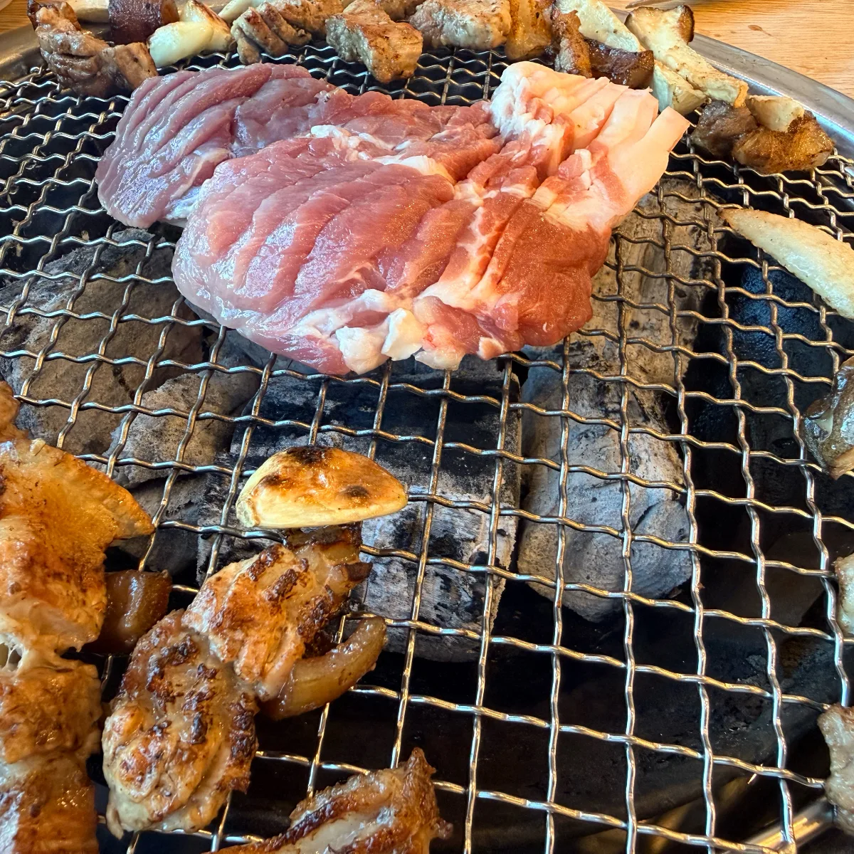 炭火の網に載せた豚肉とキノコ