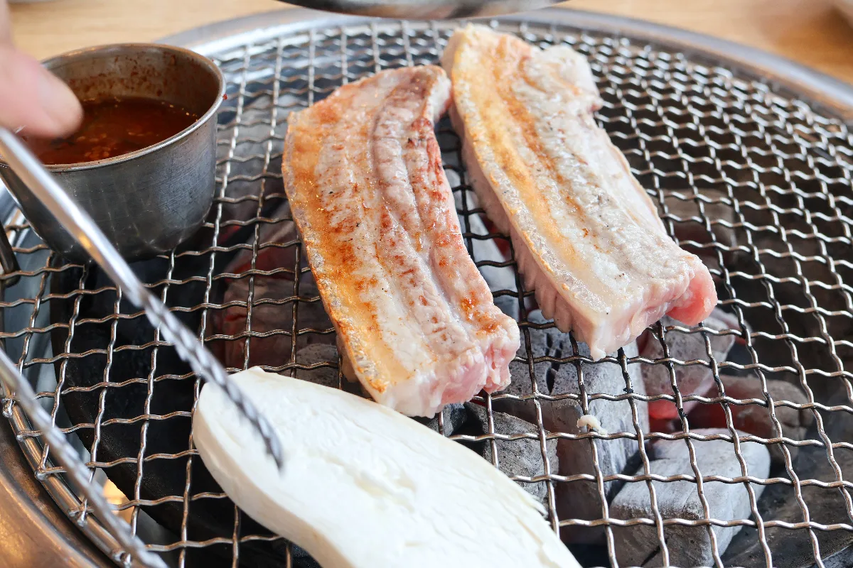 炭火で焼く厚切りの豚バラ肉