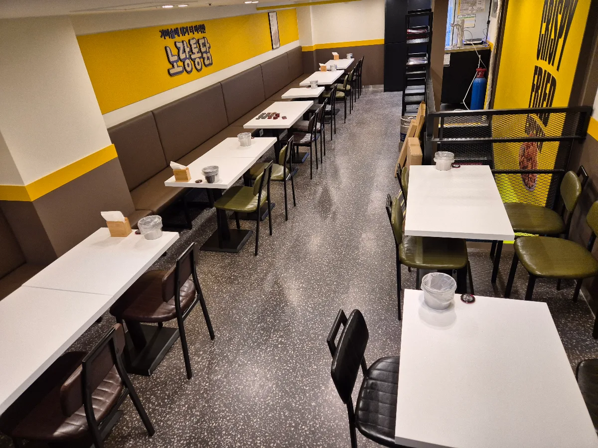 ノラントンタッ 明洞店 — 黄色い壁に沿って並ぶテーブル席