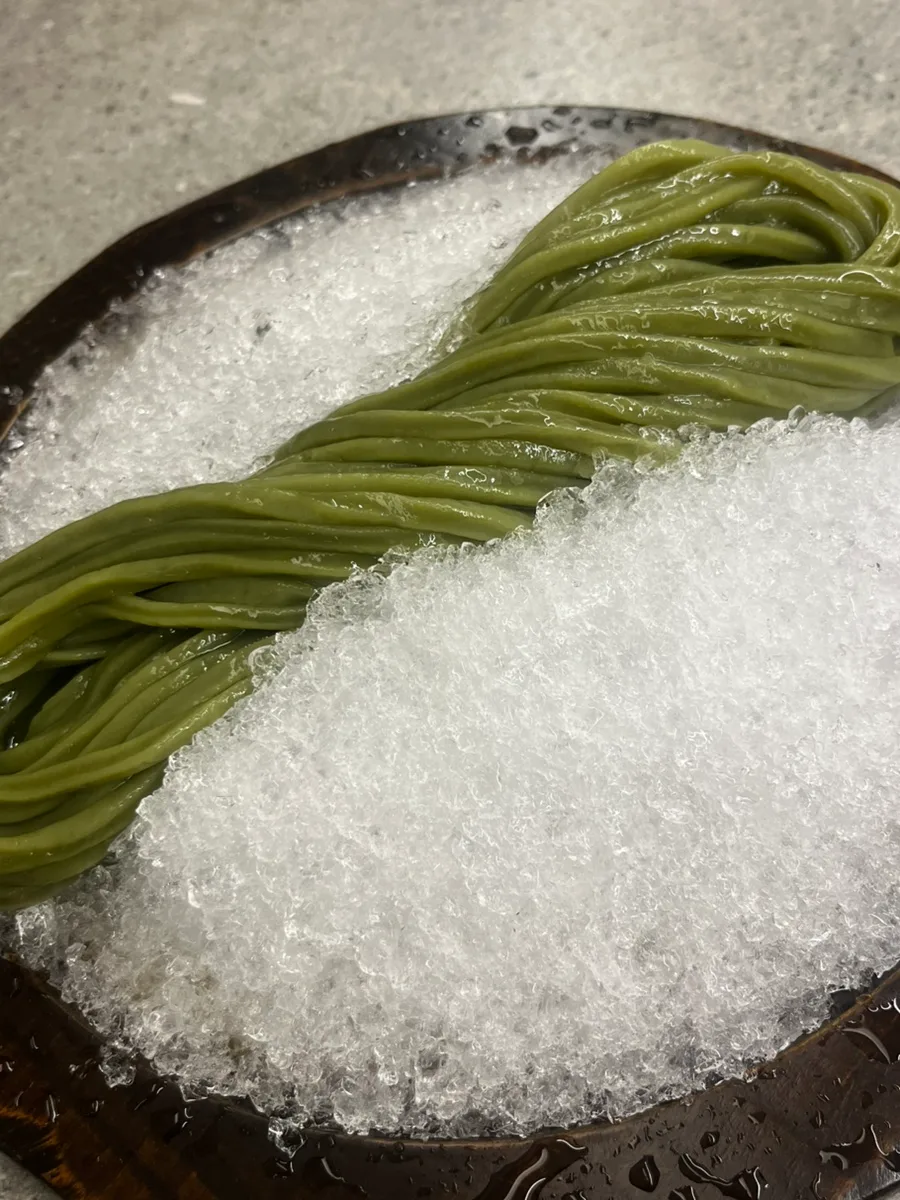 氷に沿って盛られた緑色の麺