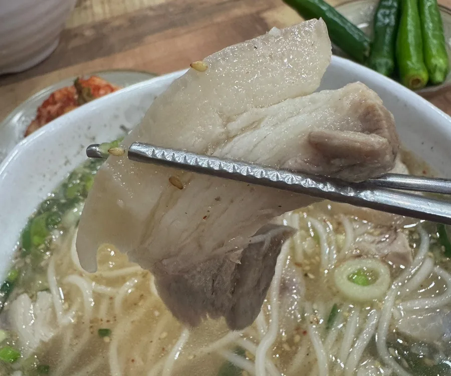 脂身の付いた豚肉を箸で持ち上げたところ