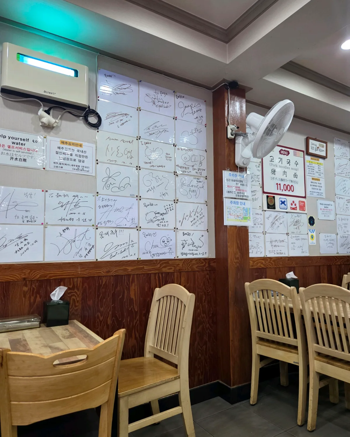サイン色紙が並ぶ店内の壁と木のテーブル