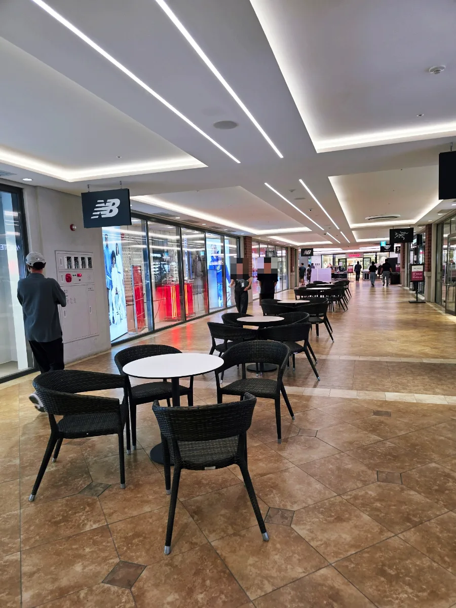 坡州プレミアムアウトレット — 店が並ぶ通路と休憩テーブル