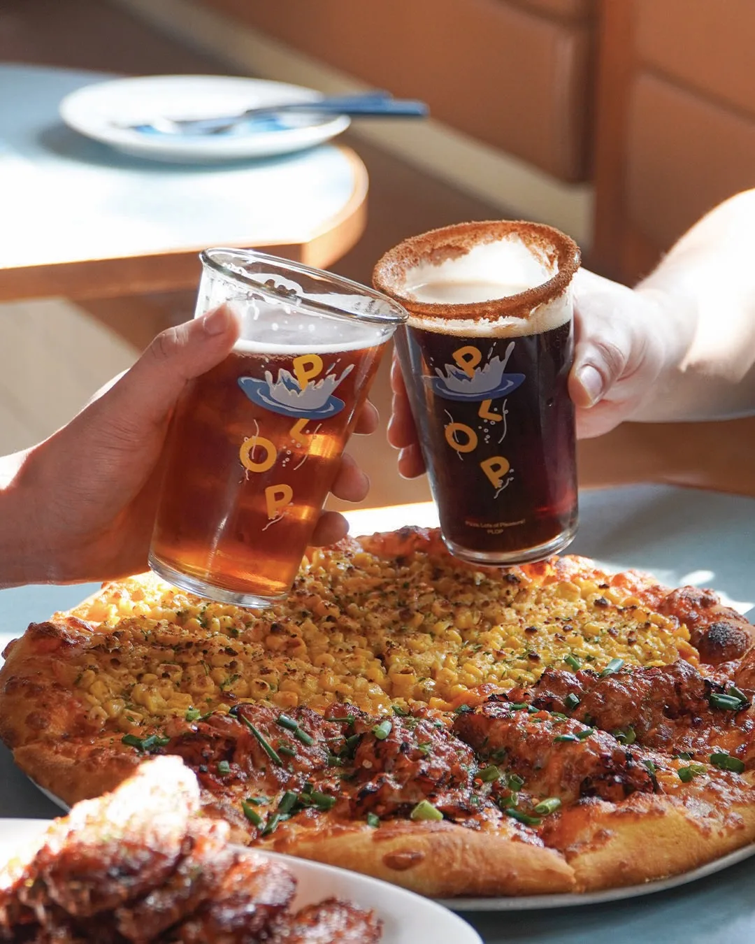 PLOPのグラスで乾杯するビールとコーンのピザ