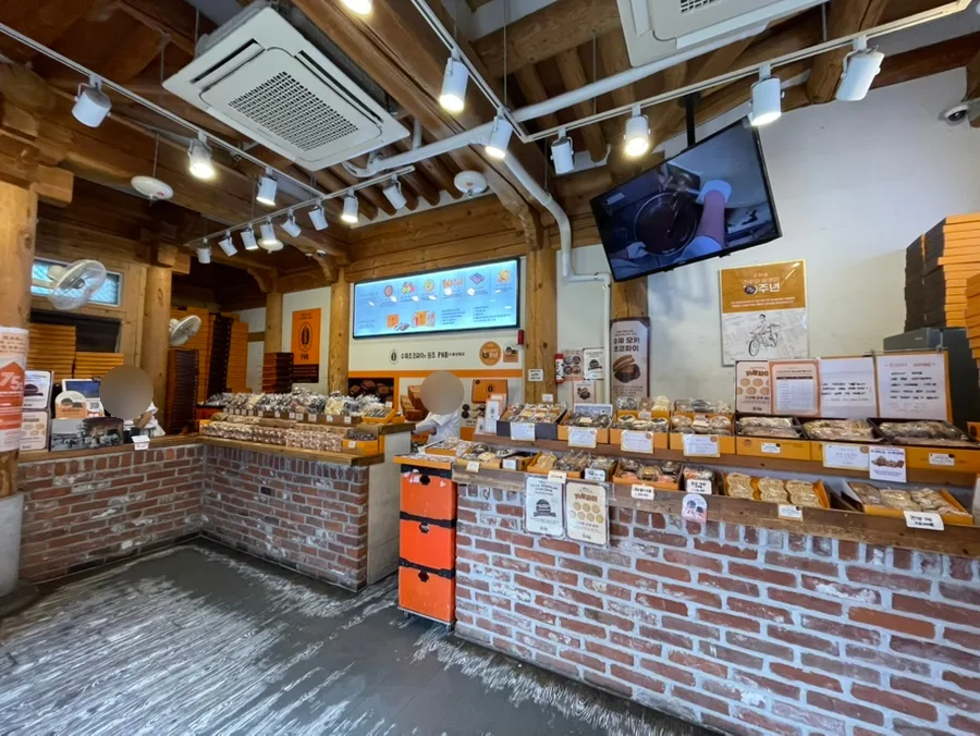 PNB豊年製菓 韓屋村1号店 — 木の梁とレンガ造りの商品カウンター