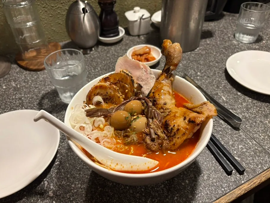 骨付きの鶏もも肉をのせた赤ラーメン