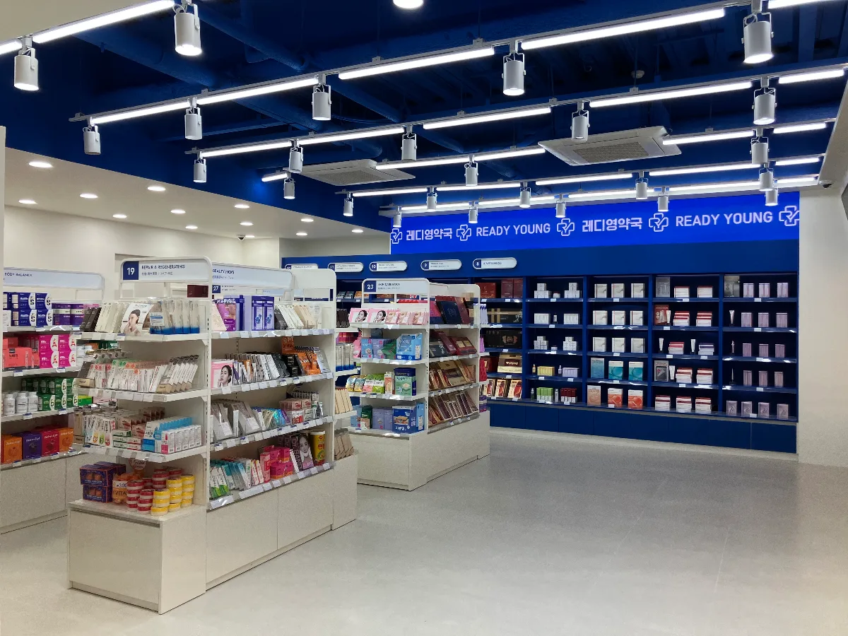 レディヤング薬局 釜山店 — 青い天井と白い商品棚が並ぶ店内
