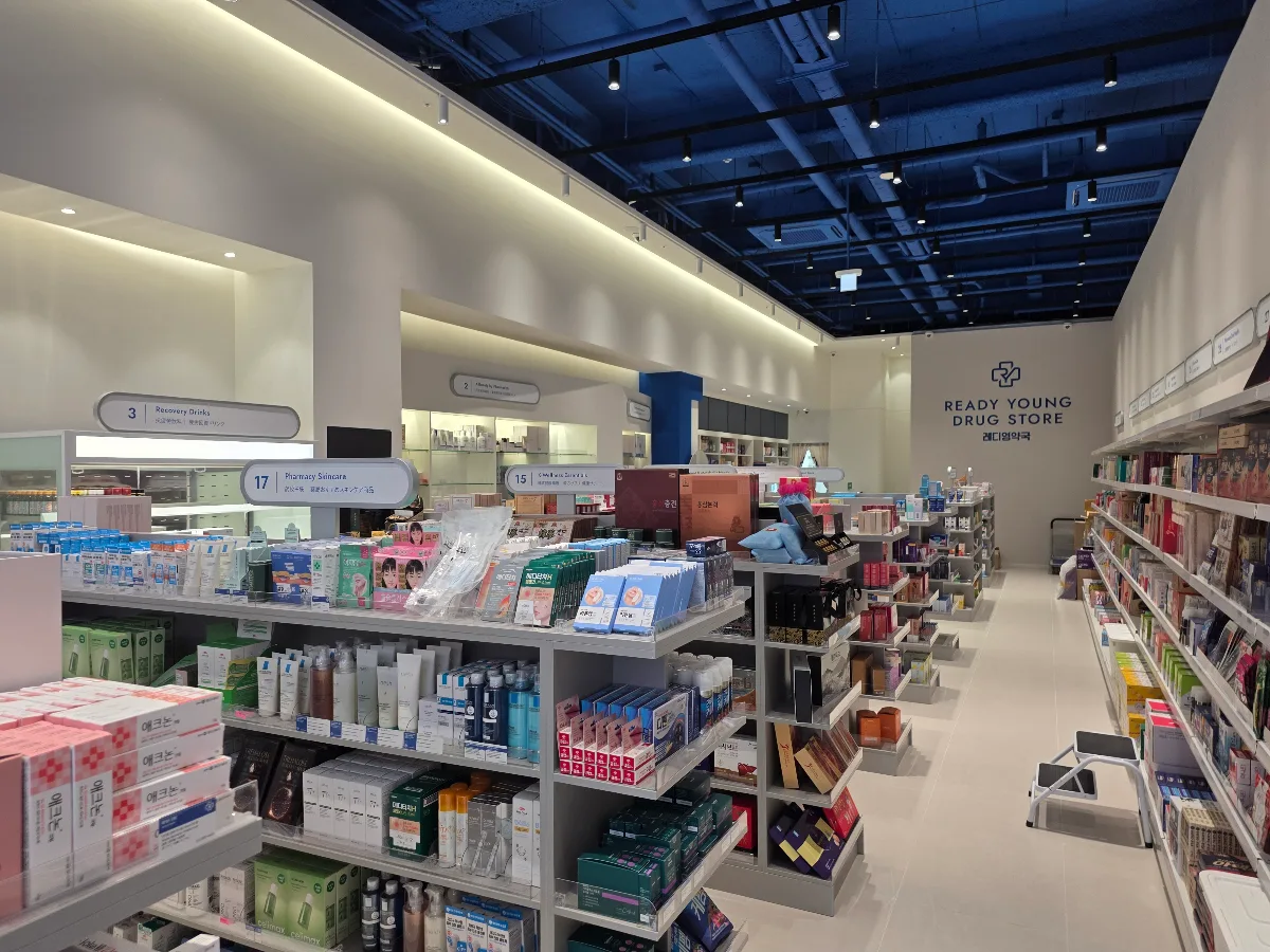 レディヤング薬局 明洞店 — 青い天井の下に並ぶ商品棚