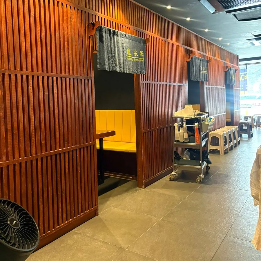 龍泉荘 本店 — 木の仕切りと通路に並ぶ椅子