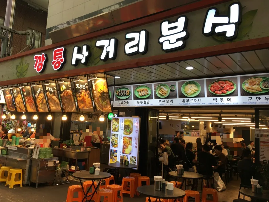 サゴリプンシク — 光る店名看板と店先のテーブル