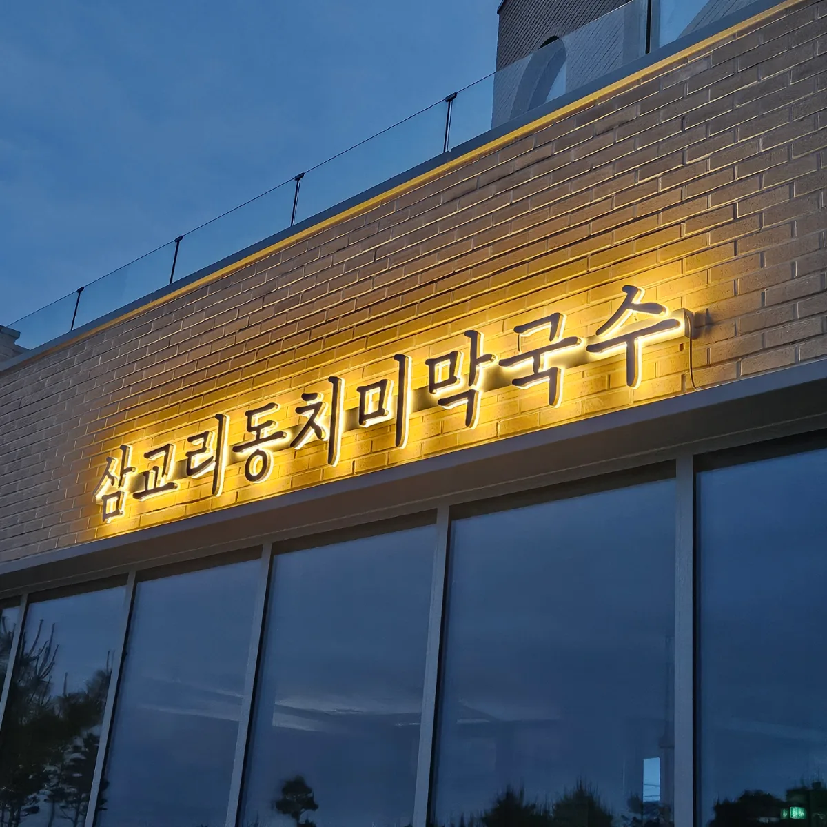 サムギョリ・トンチミマッククス 南項津店 — 夜に明かりがともる店名の看板