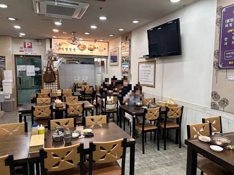 西面ミルミョン — 木製の椅子とテーブルが並ぶ店内
