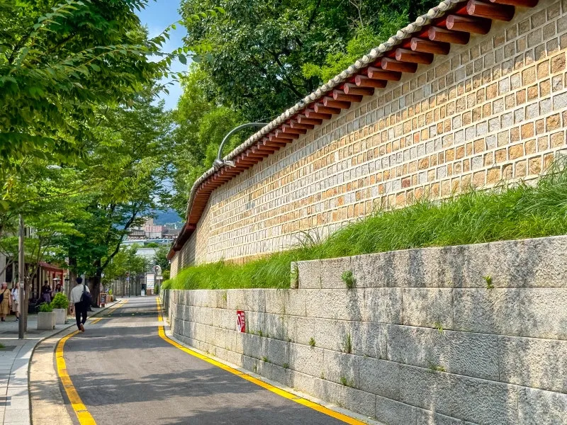 瓦屋根をのせた石垣と緑に沿う道