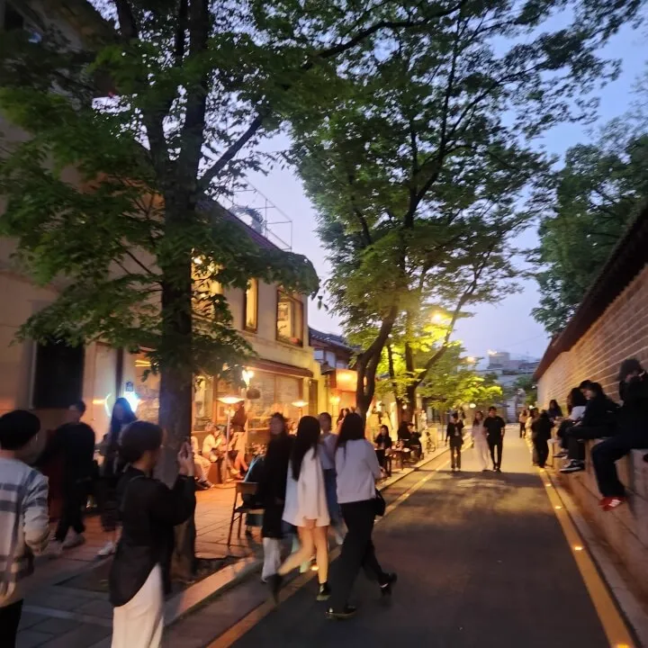 夕暮れ、石垣沿いの道を歩く人たち