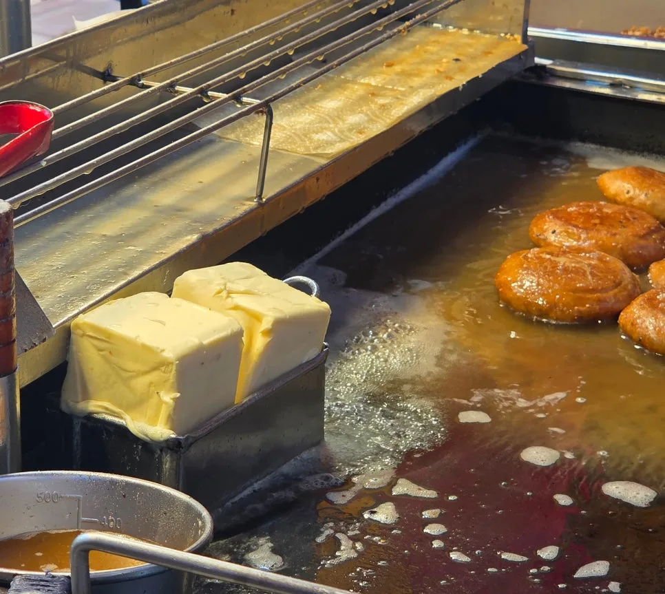 油脂のかたまりの横で揚げ焼きにされるホットク