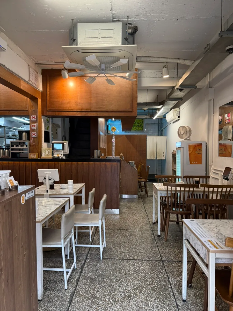 新発園 — 木の椅子と白いテーブルが並ぶ店内