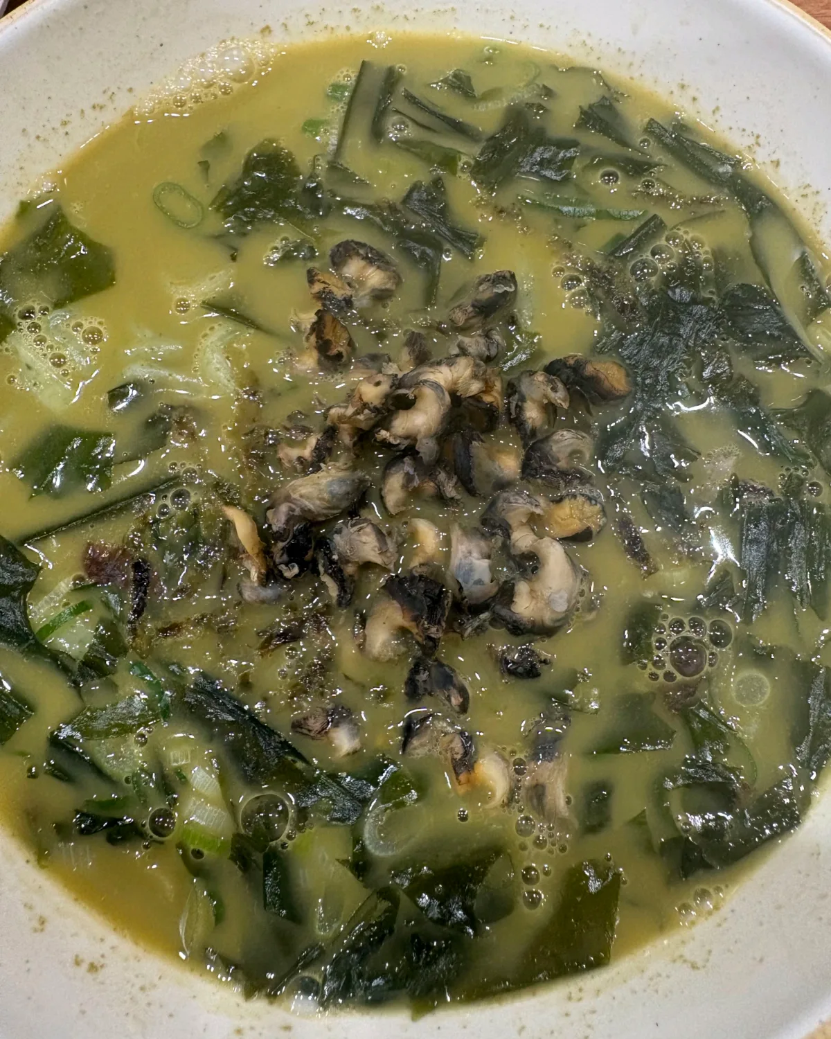 貝を盛った緑色のスープ