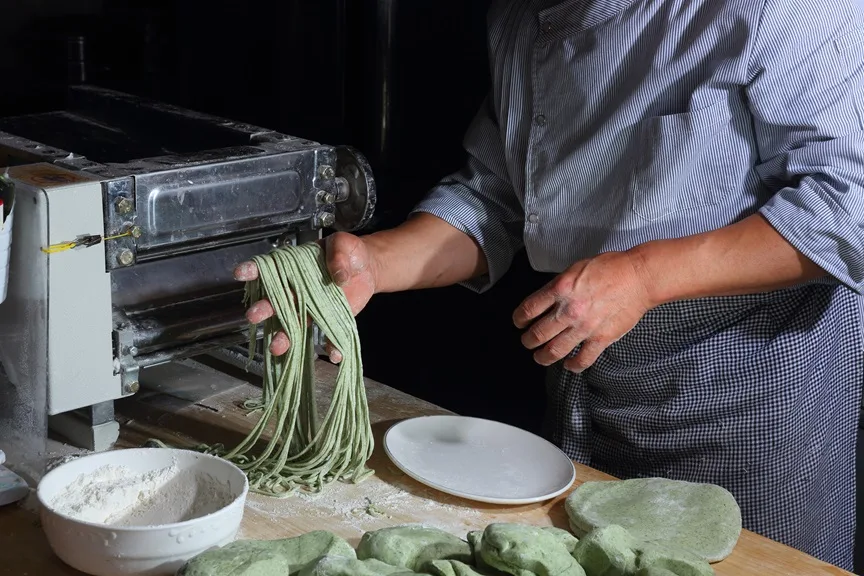 緑色の生地を製麺機で麺にするところ