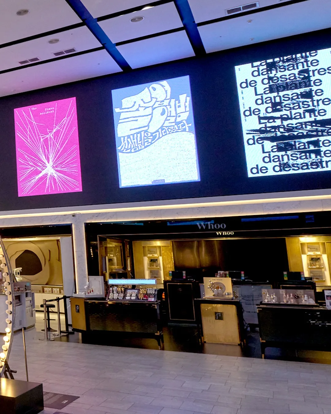 新世界免税店 明洞店 — 化粧品ブランドのカウンターと大型スクリーン