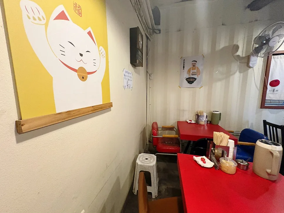 招き猫の絵と赤いテーブルの店内