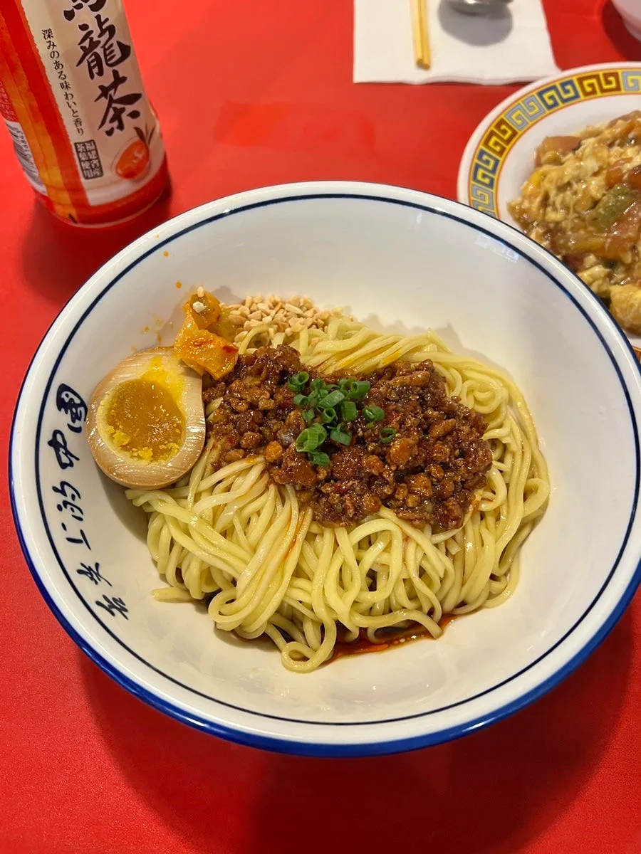XIHONGSHI — 赤いテーブルに置かれた汁なし担々麺
