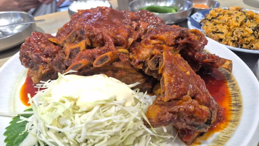 赤いタレの骨付き肉と千切りキャベツ