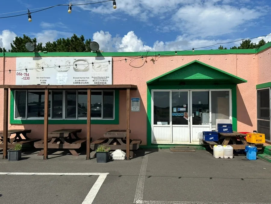 ソグムバチスニネ — ピンクの壁と緑のひさしの店構え