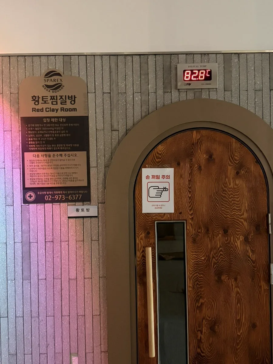 温度計が82.8℃を示す黄土チムジル部屋のアーチ型の木の扉