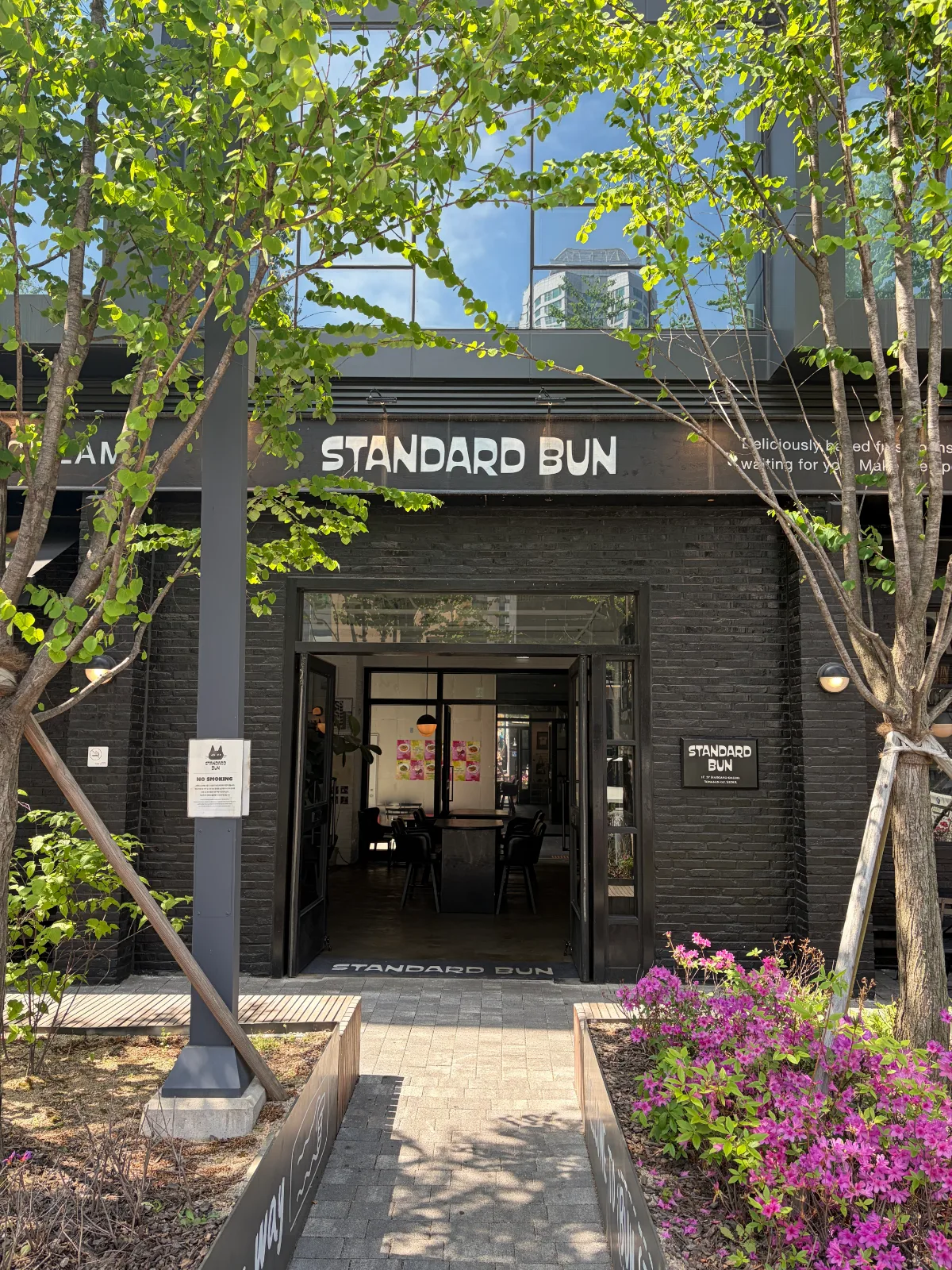 STANDARD BUN 龍山店 — 木々に囲まれた黒い店舗入口