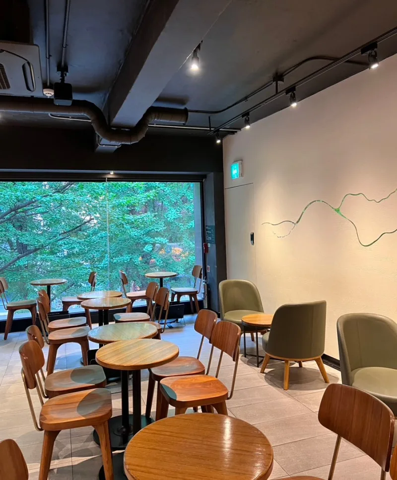 スターバックス 梨大店 — 緑が見える窓辺と丸テーブル