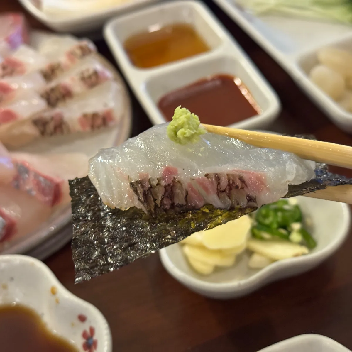 わさびをのせ、海苔で包んだ刺身のひと切れ