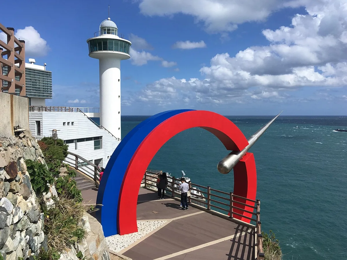 白い影島灯台と、赤と青のアーチがある展望デッキ
