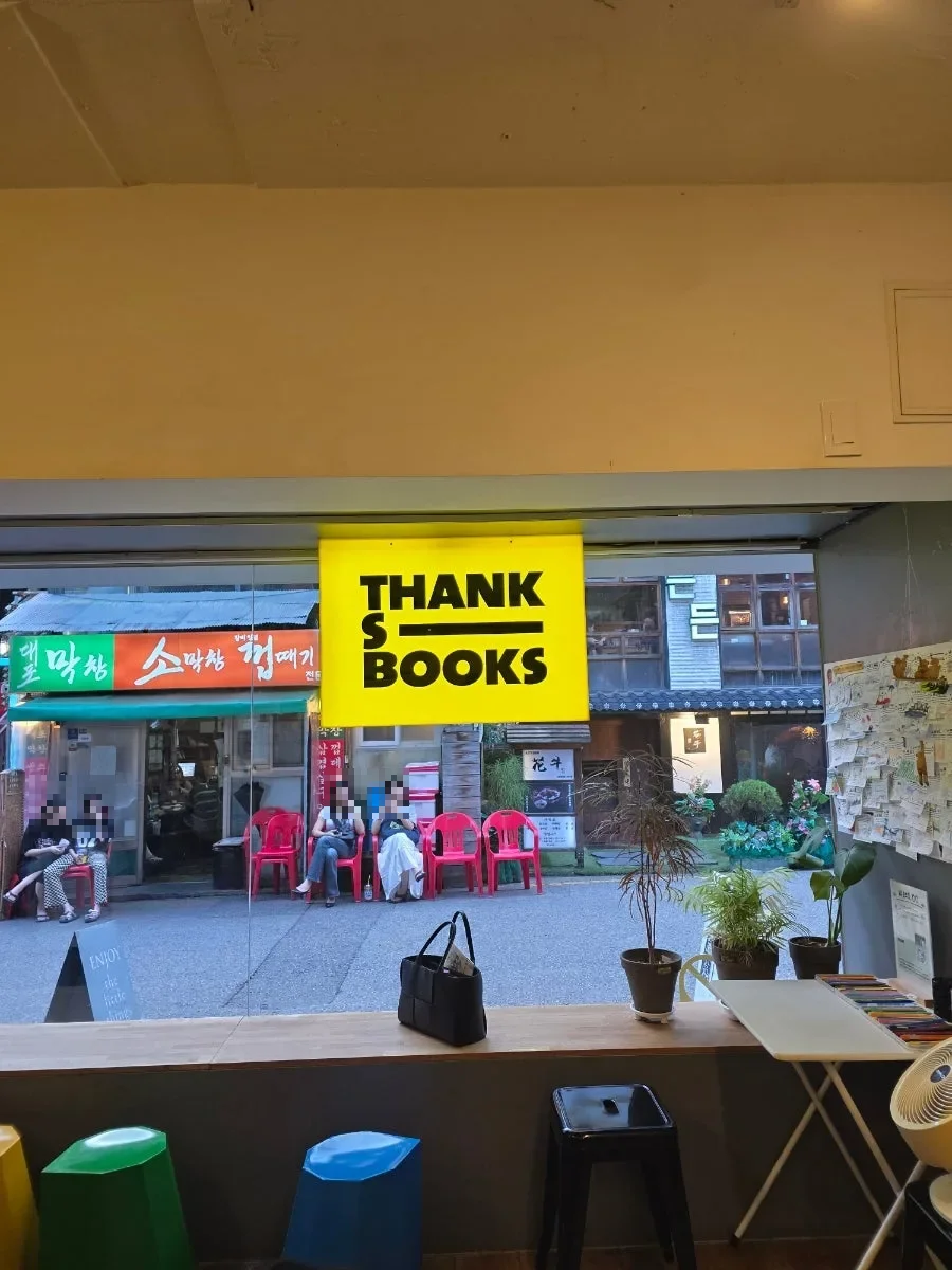 THANKS BOOKS — 店内から見た黄色い看板と窓辺のカウンター