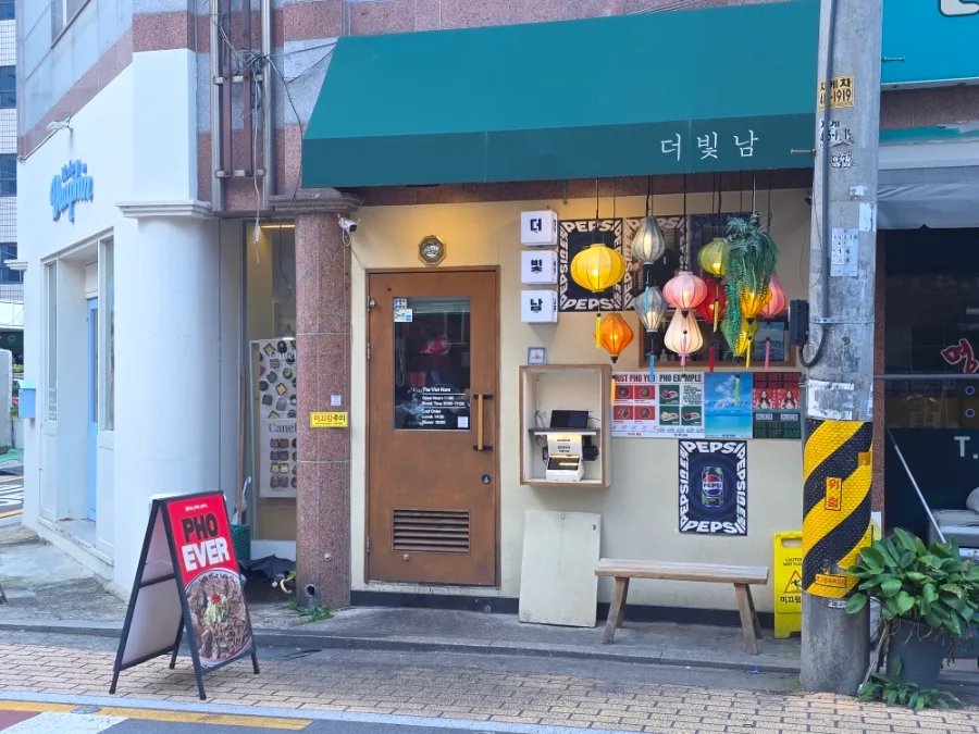 The Viet Nam 本店 — 緑のひさしと木製ドアの店先