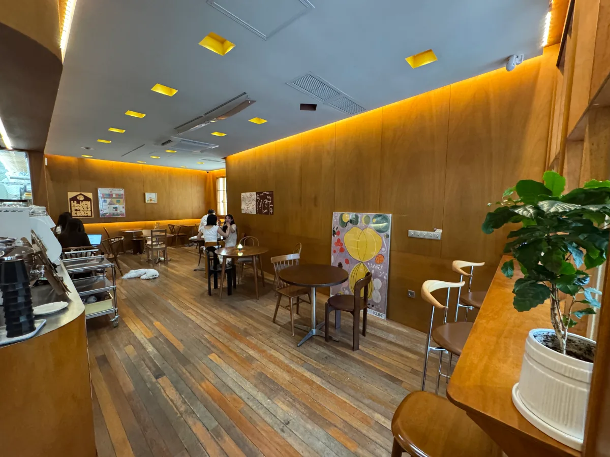 TKii 島山店 — 木の壁に沿って並ぶテーブル席