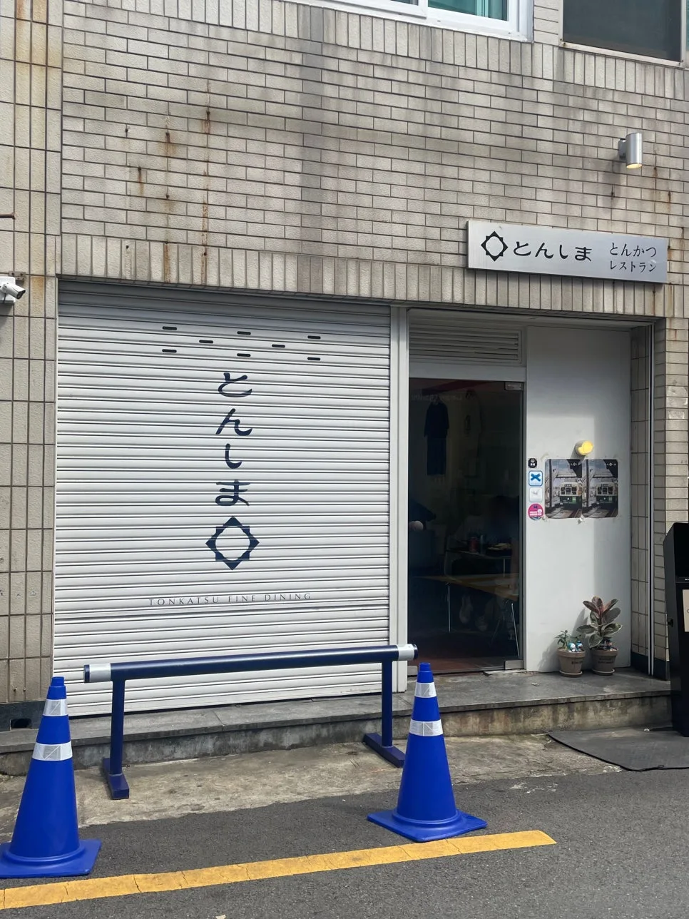 「とんしま」の看板と白いシャッターの店先