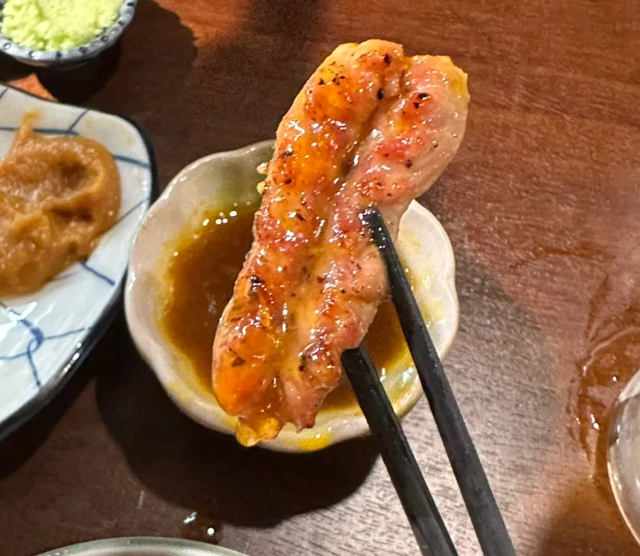 焼いた鶏肉を卵黄入りのタレにつけるところ
