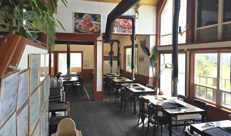 トゥンタンジ 涯月黒豚 本店 — 大きな窓沿いに並ぶ焼肉テーブル