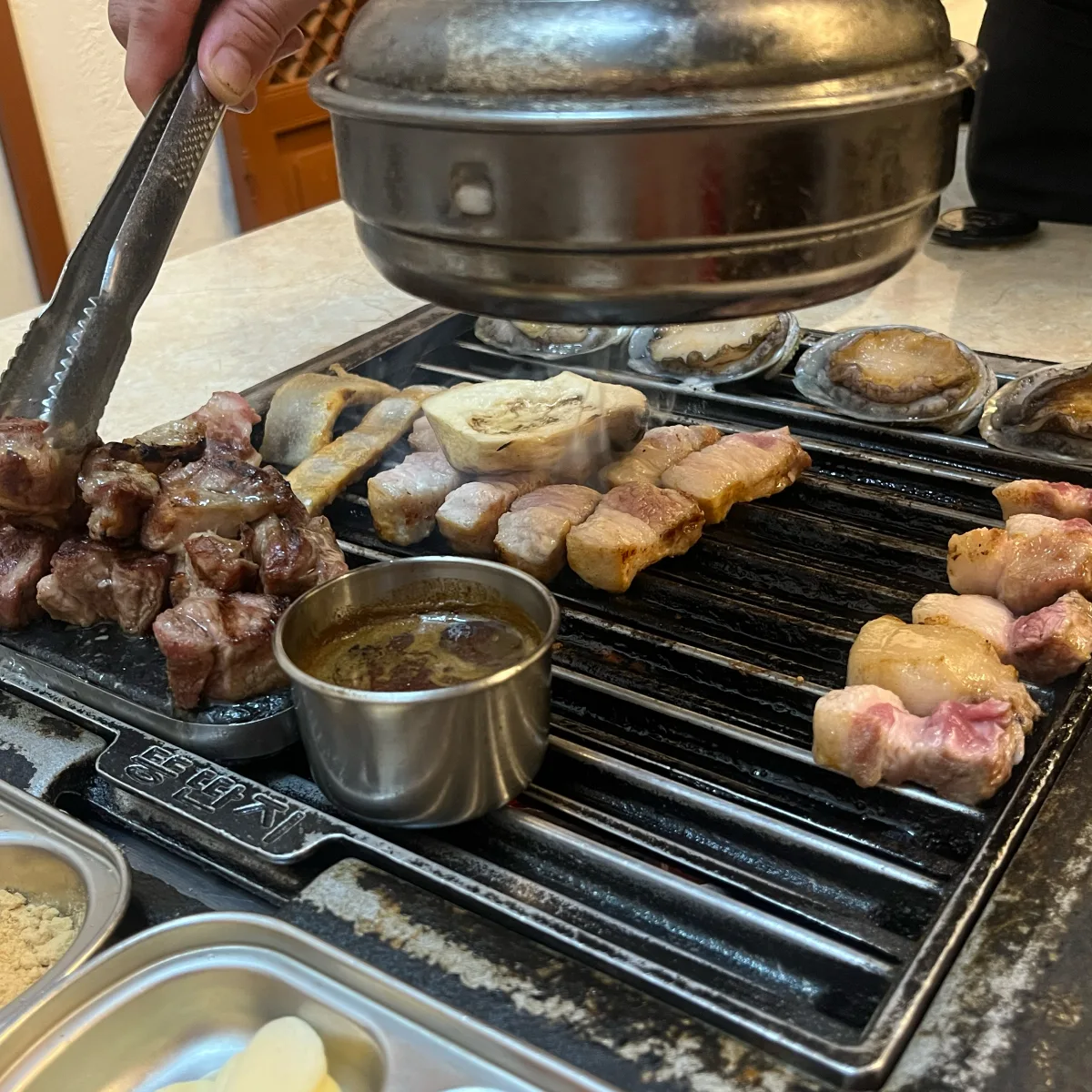 トングで豚肉を焼く手元