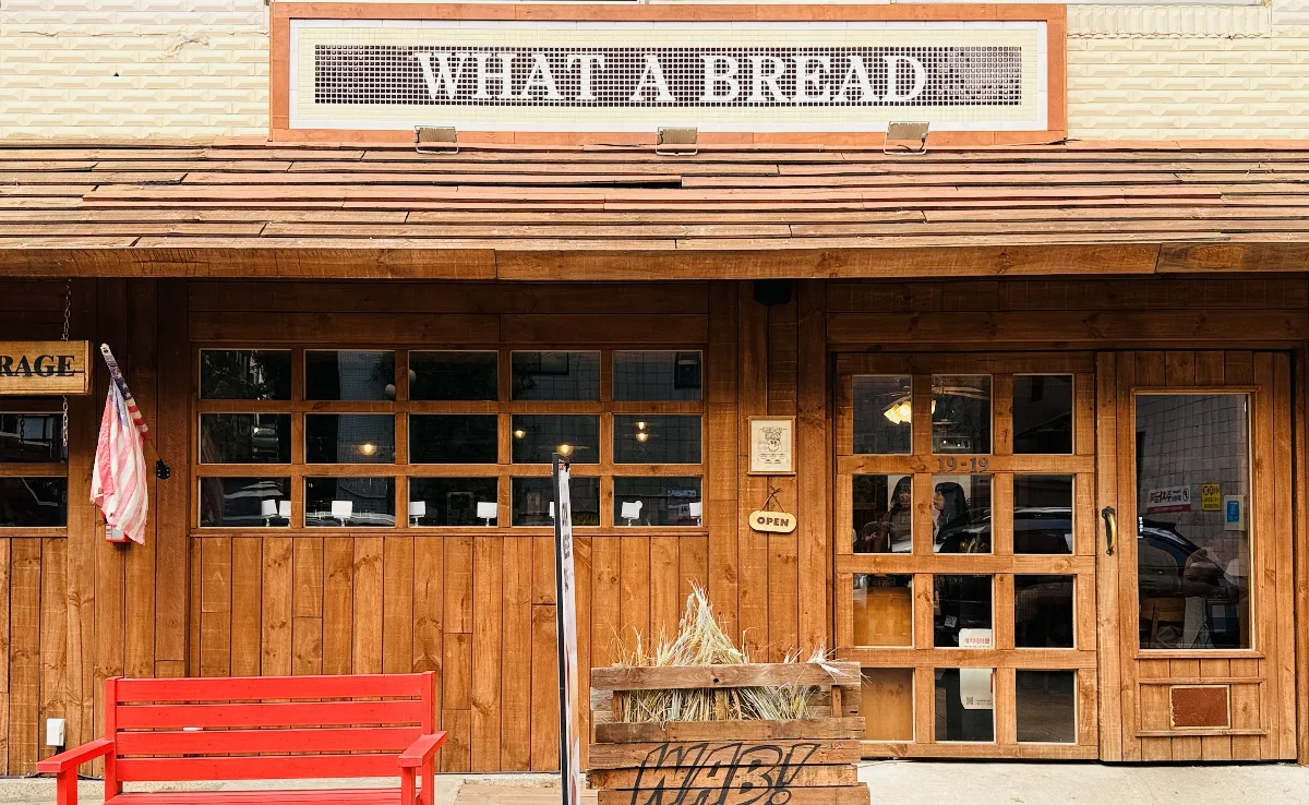 WHAT A BREAD 龍山店 — 木造りの店構えと赤いベンチ