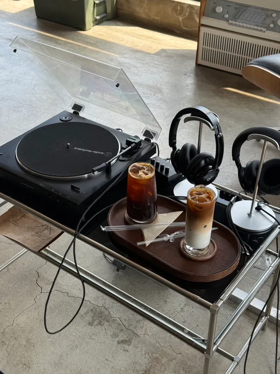 ターンテーブルとヘッドホン2つ、ドリンクが並ぶ二人席