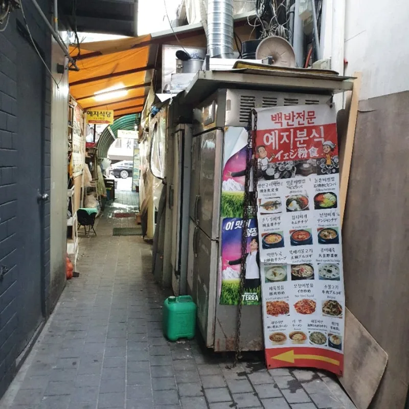 「백반전문 예지분식 イェジ粉食」の立て看板がある路地