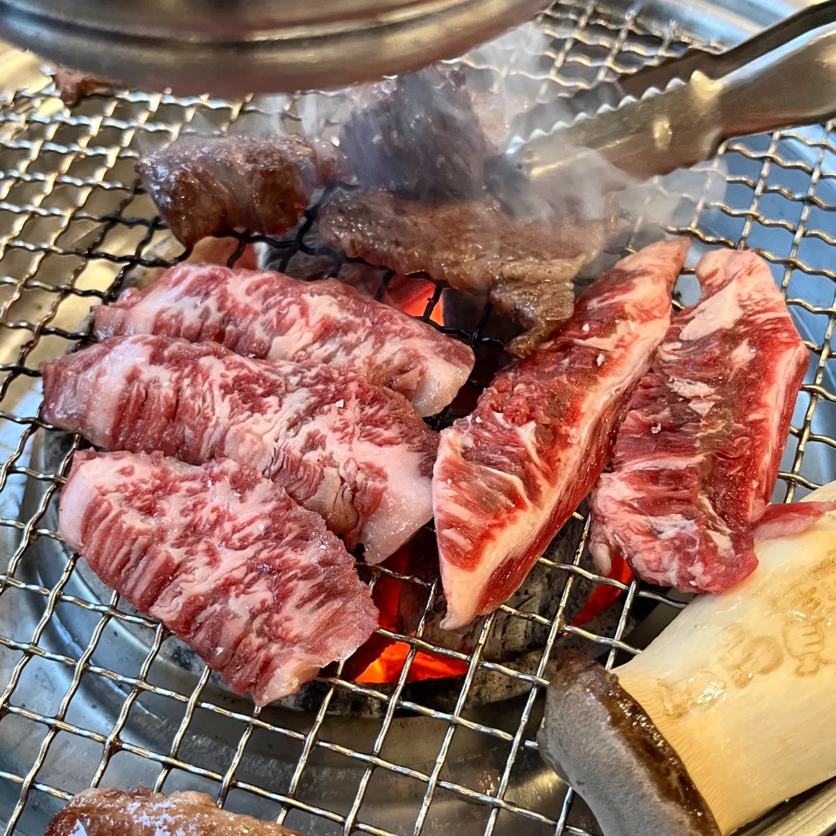 炭火の網で焼く霜降り牛肉
